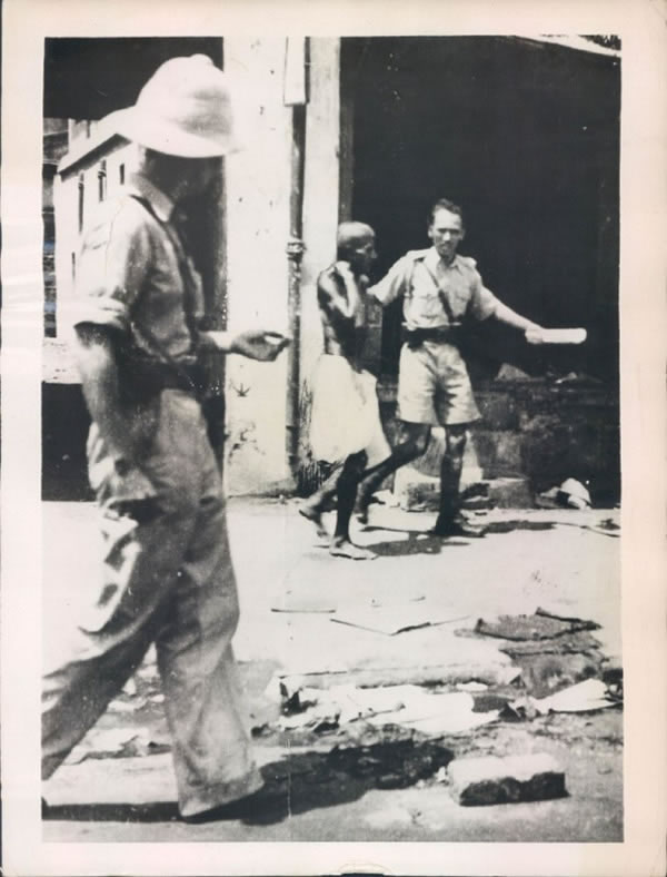 An Indian soldier leads away a Hindu rioter in a debris strewn street of Bombay (Mumbai) - 1946