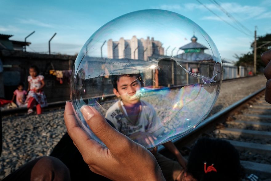 Kids Are Playing With A Balloon While Sitting On The Active Railway Tracks In A Slum Area Next To Jakarta Kota Railway Station